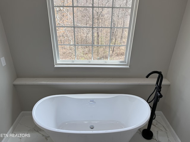 bathroom featuring a soaking tub, marble finish floor, and baseboards