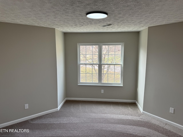 spare room featuring a textured ceiling, baseboards, and carpet