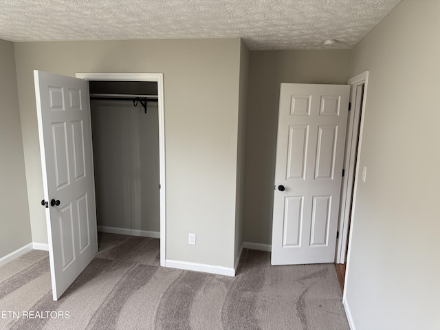 unfurnished bedroom with a closet, carpet flooring, a textured ceiling, and baseboards