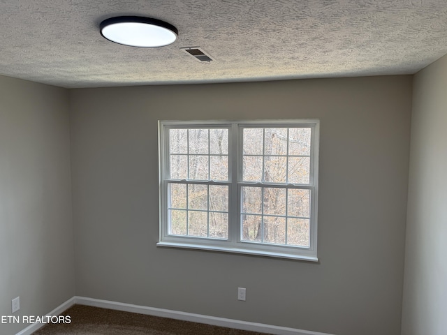 unfurnished room featuring plenty of natural light, visible vents, and a textured ceiling