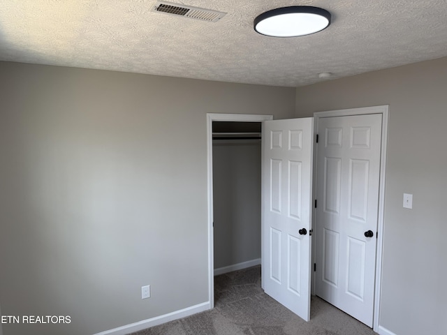 unfurnished bedroom with carpet, visible vents, baseboards, a closet, and a textured ceiling