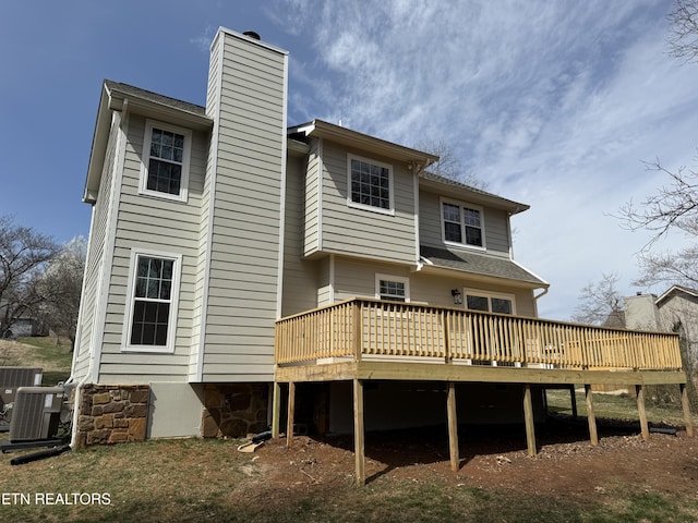 rear view of house with central AC, a deck, and a chimney