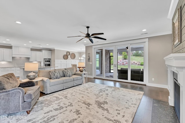 living area with dark wood-style floors, a fireplace with flush hearth, recessed lighting, ceiling fan, and crown molding