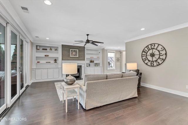 living area featuring dark wood-type flooring, a fireplace, baseboards, and ornamental molding