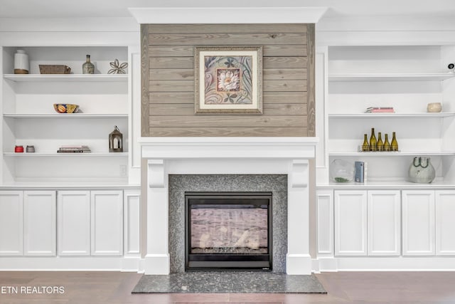 details with a fireplace, built in shelves, and wood finished floors