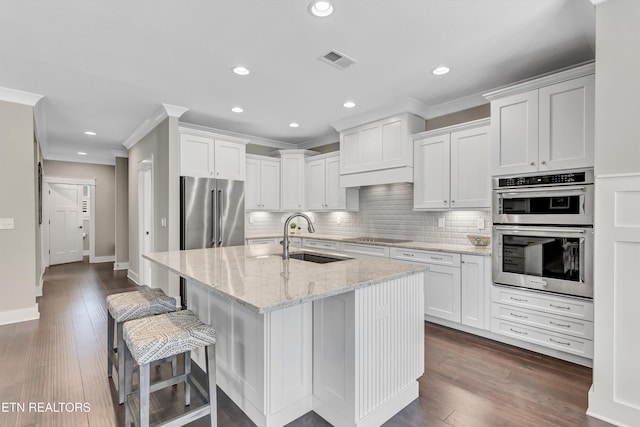 kitchen featuring visible vents, a sink, backsplash, appliances with stainless steel finishes, and crown molding