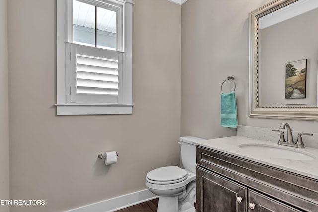 bathroom featuring toilet, vanity, baseboards, and wood finished floors