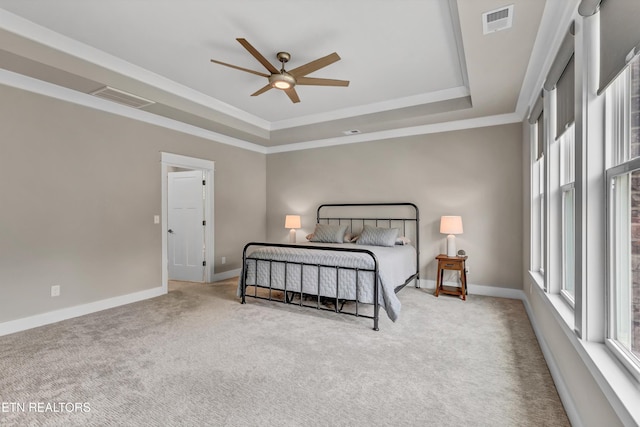 carpeted bedroom featuring visible vents, a raised ceiling, and multiple windows