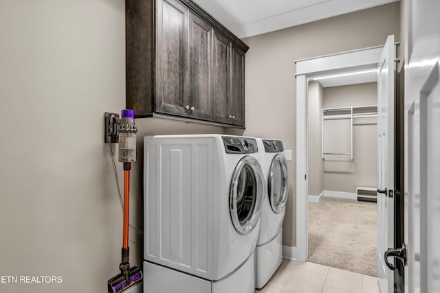 washroom featuring baseboards, light colored carpet, light tile patterned flooring, cabinet space, and separate washer and dryer