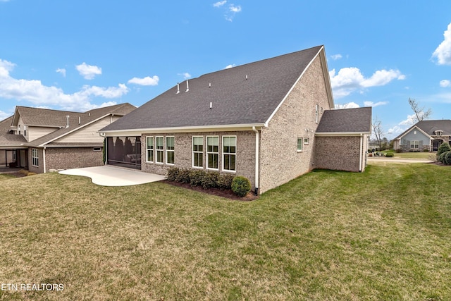 rear view of property featuring a yard, a patio, and a sunroom