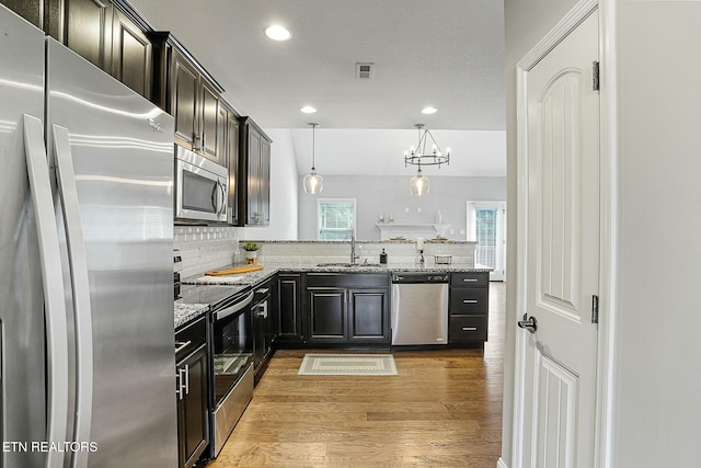 kitchen featuring visible vents, a sink, tasteful backsplash, appliances with stainless steel finishes, and light wood finished floors