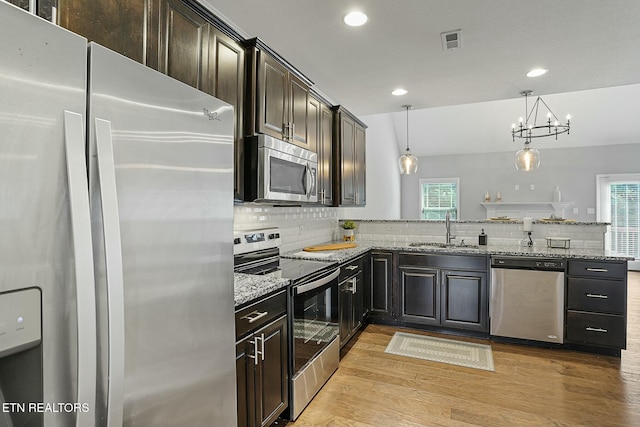 kitchen featuring visible vents, a sink, tasteful backsplash, appliances with stainless steel finishes, and light wood finished floors