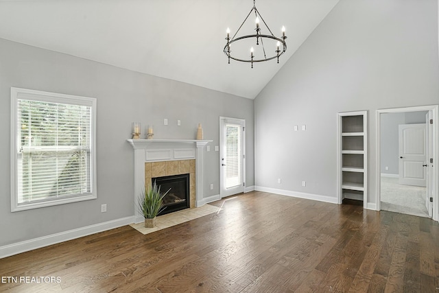 unfurnished living room with a notable chandelier, plenty of natural light, and wood finished floors