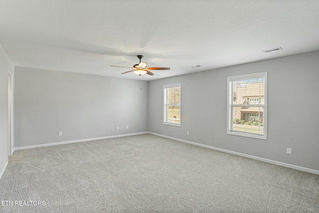 unfurnished room with light carpet, visible vents, baseboards, and a ceiling fan