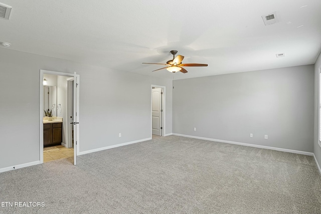 unfurnished bedroom with visible vents, baseboards, ceiling fan, light carpet, and connected bathroom