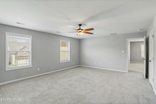 spare room with visible vents, light carpet, a textured ceiling, and a ceiling fan