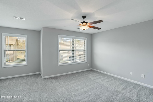 carpeted empty room featuring visible vents, baseboards, and ceiling fan