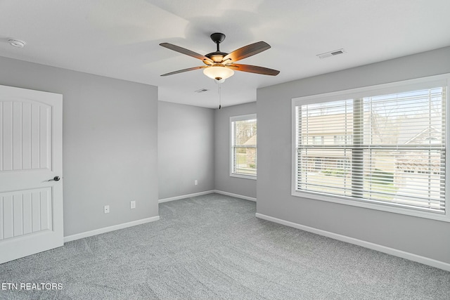 carpeted empty room with visible vents, baseboards, and a ceiling fan