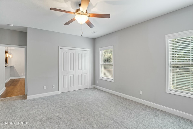 unfurnished bedroom with baseboards, visible vents, ceiling fan, a closet, and carpet flooring