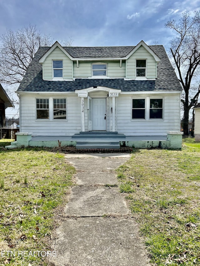 view of front of house featuring roof with shingles and a front yard