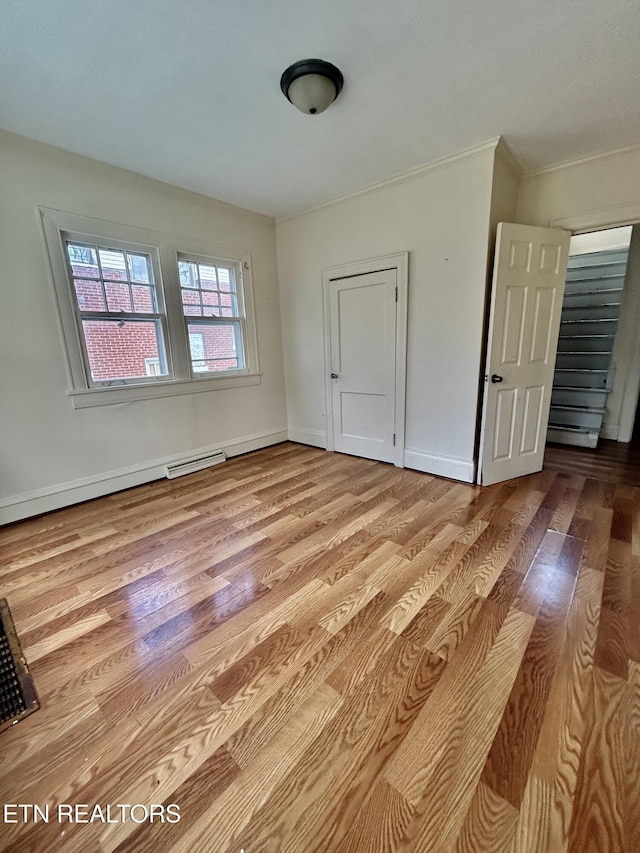 empty room with visible vents, wood finished floors, baseboards, and ornamental molding