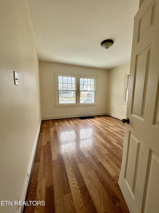 unfurnished room featuring crown molding, baseboards, and wood finished floors