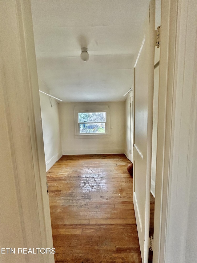 spare room with baseboards and hardwood / wood-style floors