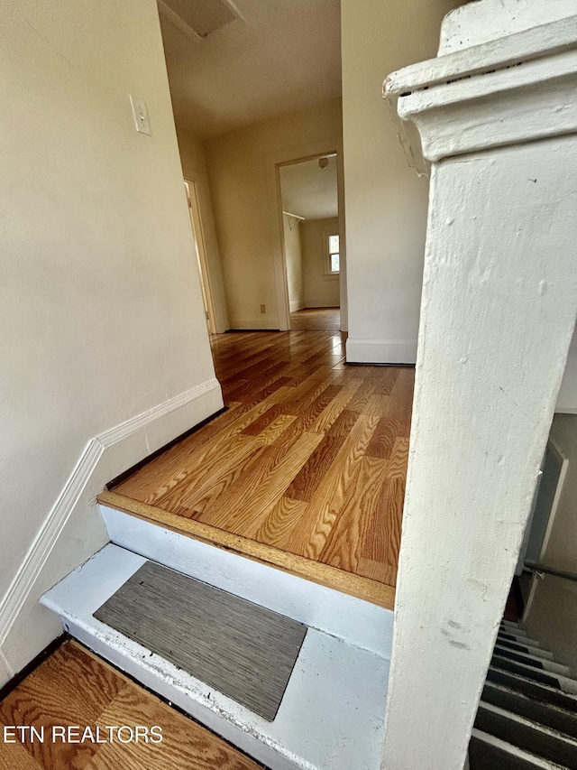 hall with baseboards and wood finished floors