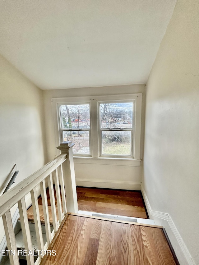 stairway featuring a wealth of natural light, baseboards, and wood finished floors