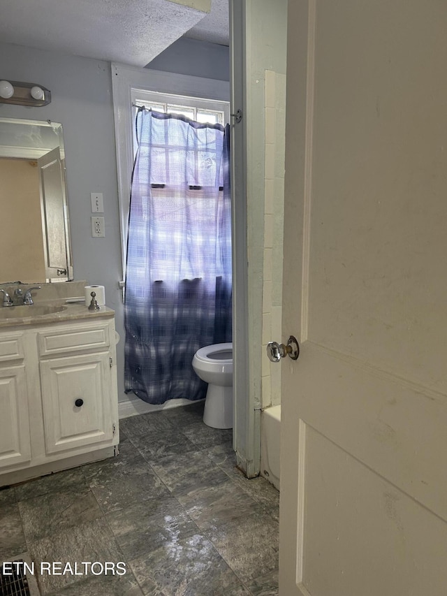 bathroom with vanity, toilet, a tub, and a textured ceiling