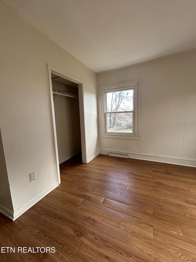 unfurnished bedroom featuring visible vents, wood finished floors, a closet, and baseboards