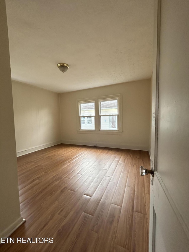 empty room featuring wood finished floors and baseboards