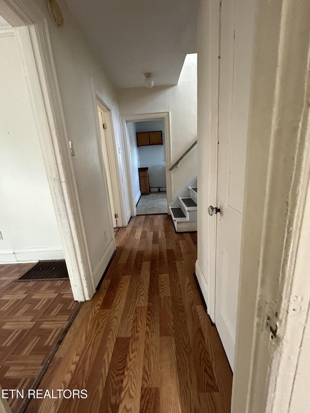 hallway featuring stairs, dark wood-style floors, and baseboards