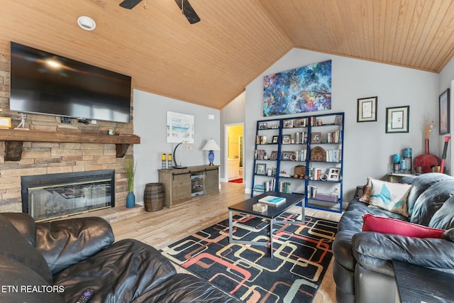 living area featuring lofted ceiling, a stone fireplace, wooden ceiling, wood finished floors, and a ceiling fan