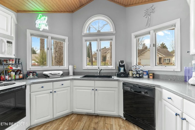 kitchen with white microwave, electric range, a sink, black dishwasher, and light wood-style floors