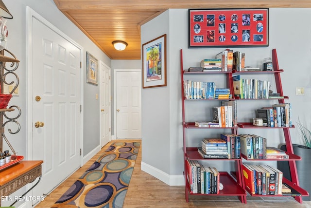 hallway featuring baseboards, wood finished floors, and wooden ceiling