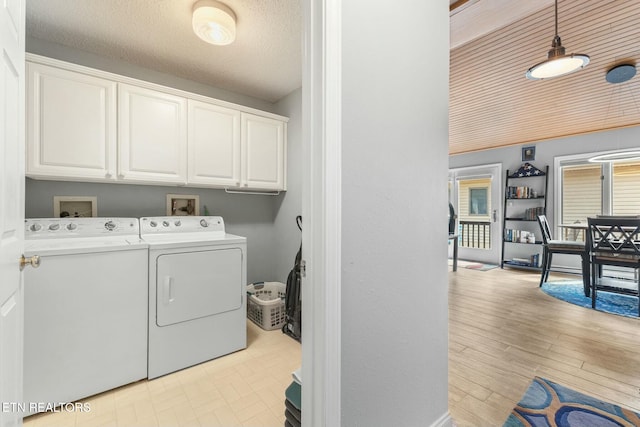 laundry area with washer and dryer, wood finished floors, cabinet space, and a textured ceiling