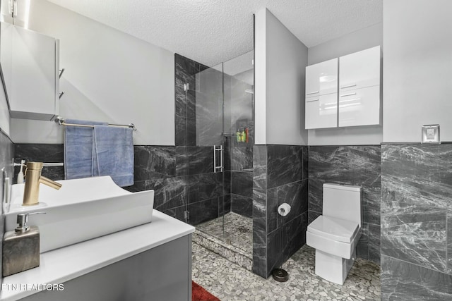 full bath with a stall shower, toilet, tile walls, and a textured ceiling