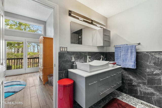 bathroom featuring a textured ceiling, wood finished floors, tile walls, wainscoting, and vanity