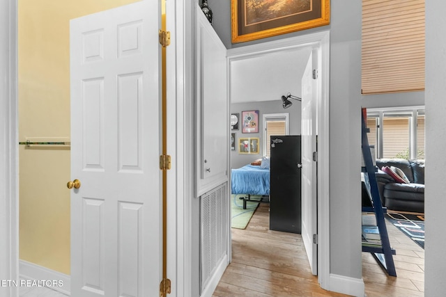 corridor with light wood finished floors and baseboards