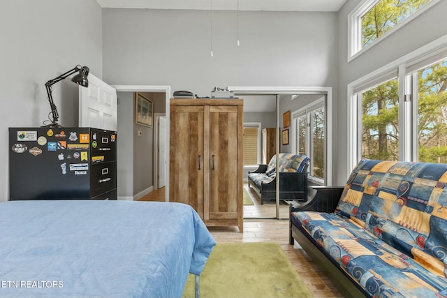 bedroom with light wood-style flooring and a towering ceiling