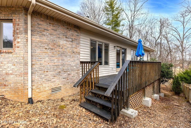 doorway to property with crawl space, brick siding, a wooden deck, and fence