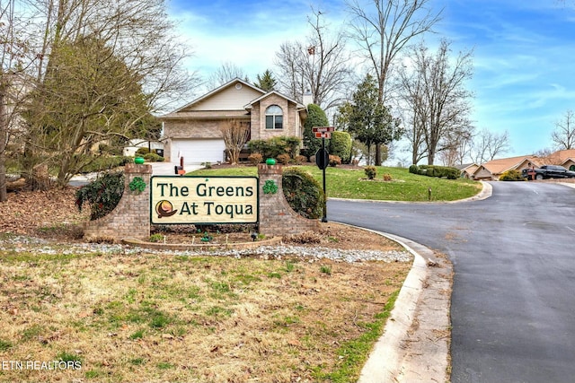 community sign with a lawn, a garage, and driveway