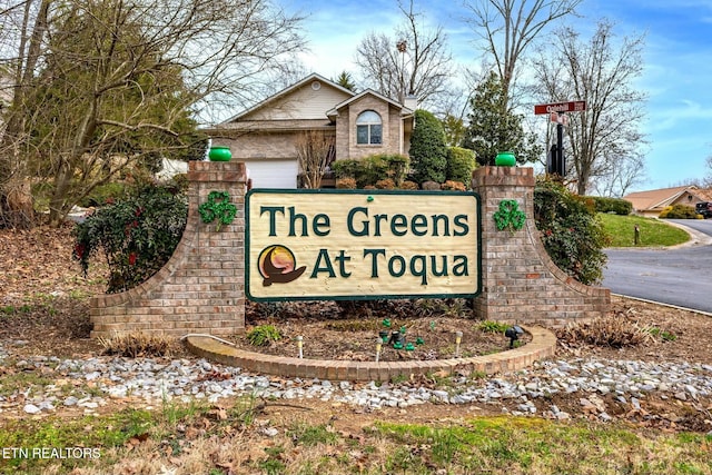 community sign featuring driveway and an attached garage