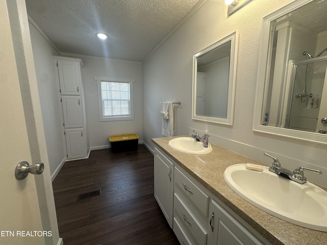 bathroom with visible vents, wood finished floors, a shower with shower door, a textured ceiling, and a sink