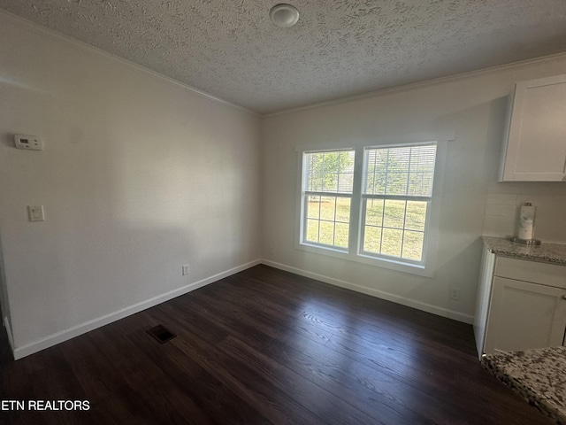 unfurnished dining area with a textured ceiling, dark wood-style floors, visible vents, and baseboards