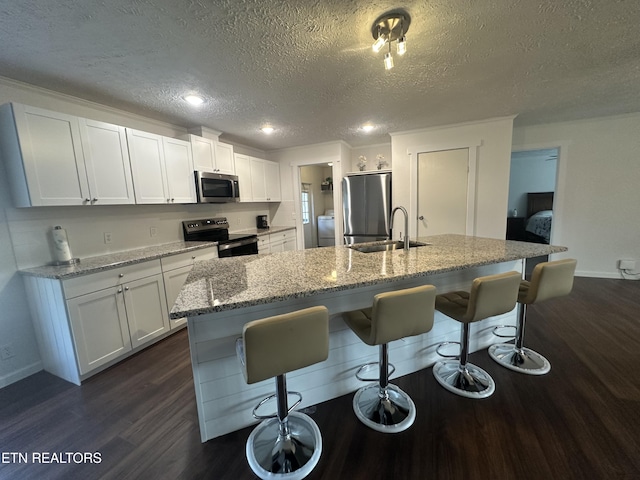 kitchen with dark wood-type flooring, a breakfast bar area, white cabinets, stainless steel appliances, and a sink