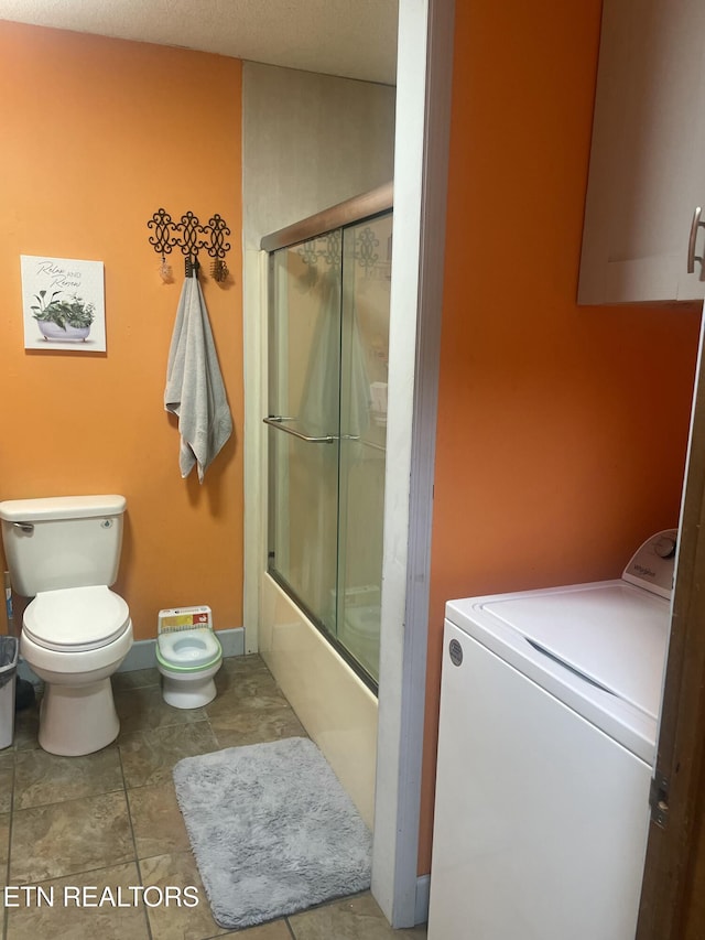 full bath with combined bath / shower with glass door, baseboards, washer / clothes dryer, and toilet