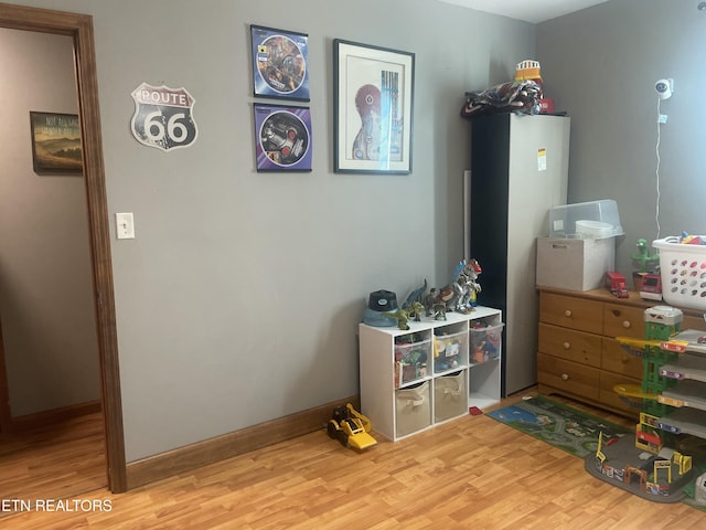 recreation room with baseboards and wood finished floors