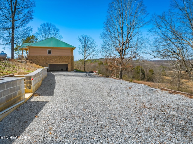 285 Redwood Dr, Dandridge, TN 37725 - view of property exterior with gravel driveway, an attached garage, and stone siding